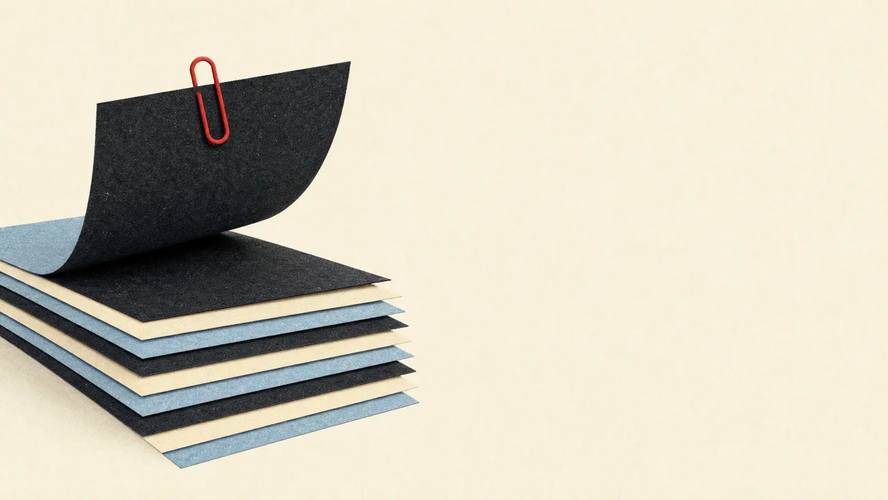 Papiercollage: ein Stapel Papierbögen, der oberste ist mit einer roten Büroklammer herausgehoben.